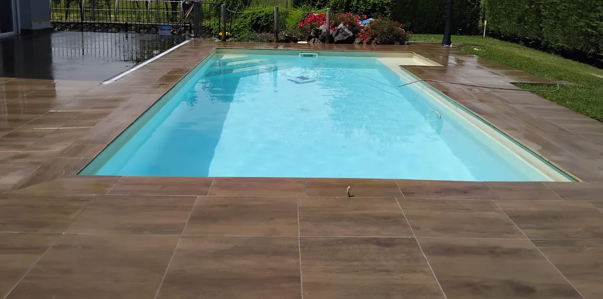 Una piscina col bordo e la pavimentazione in piastrelle effetto legno